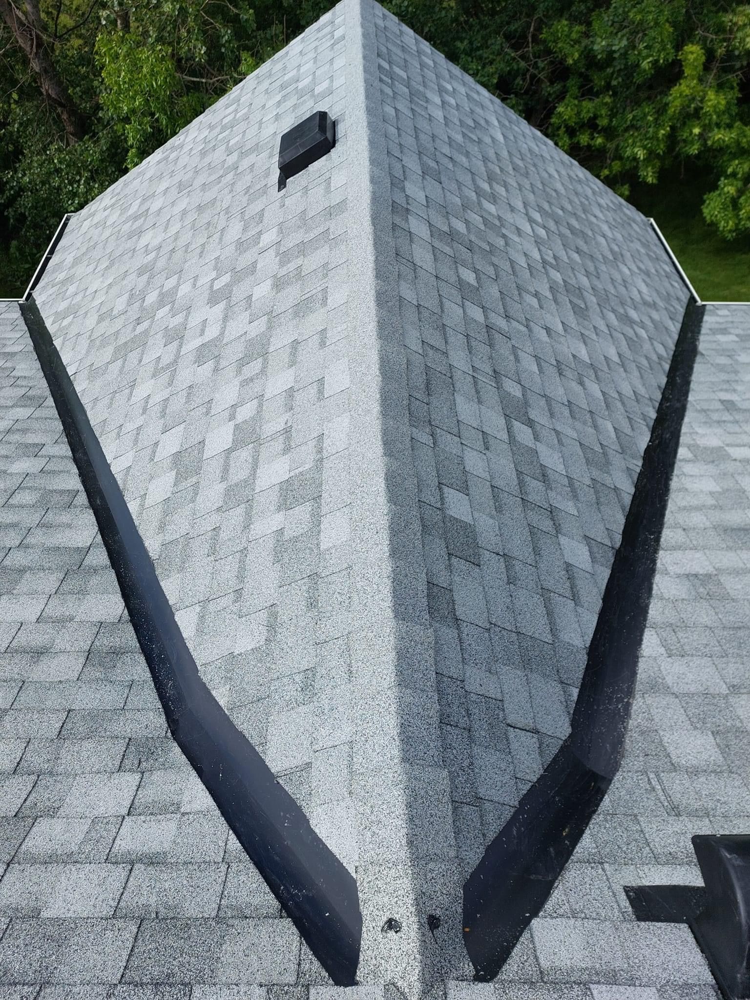 Aerial view of a gray shingled roof with two black, angled gutters.