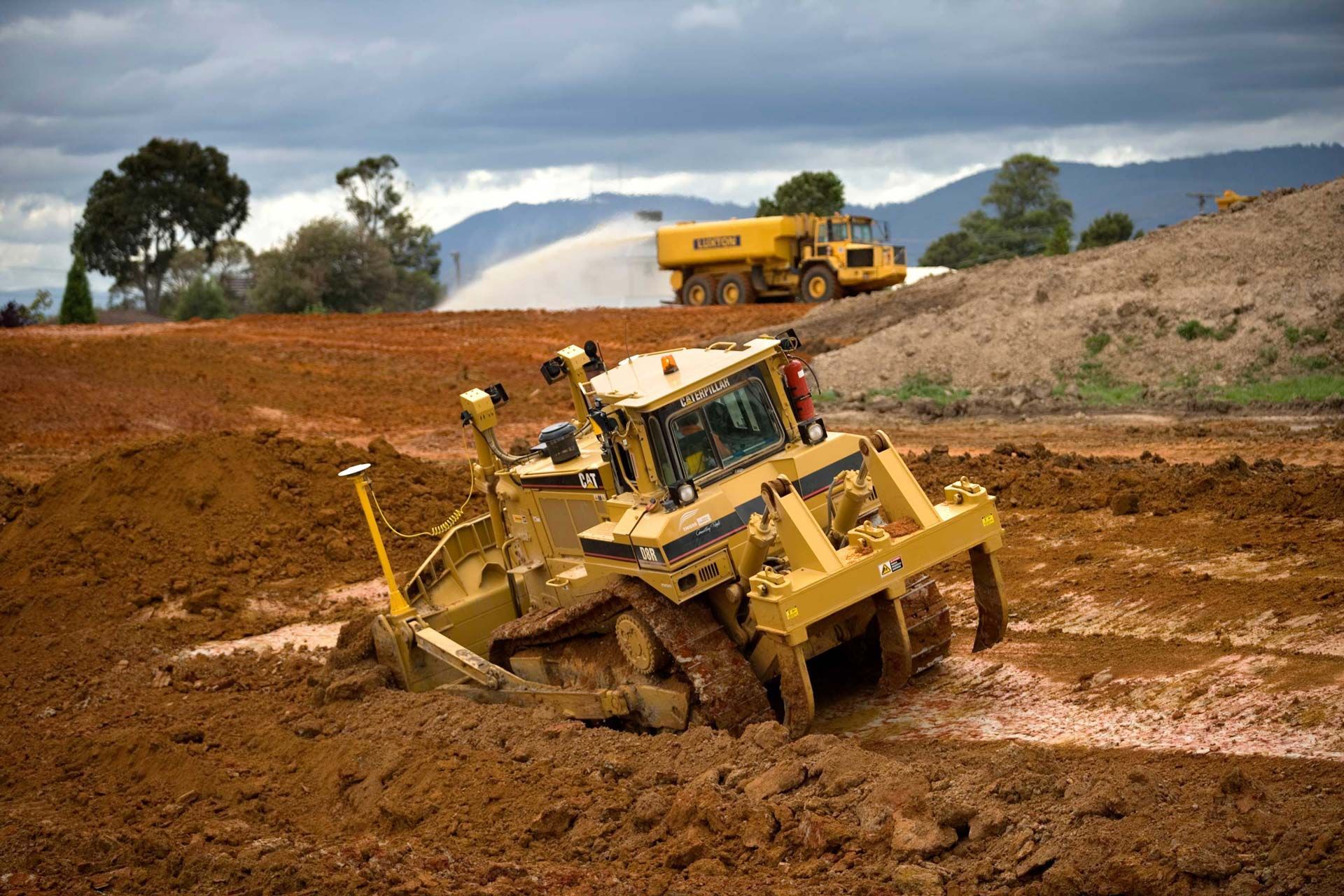 A bulldozer is driving through a muddy field.