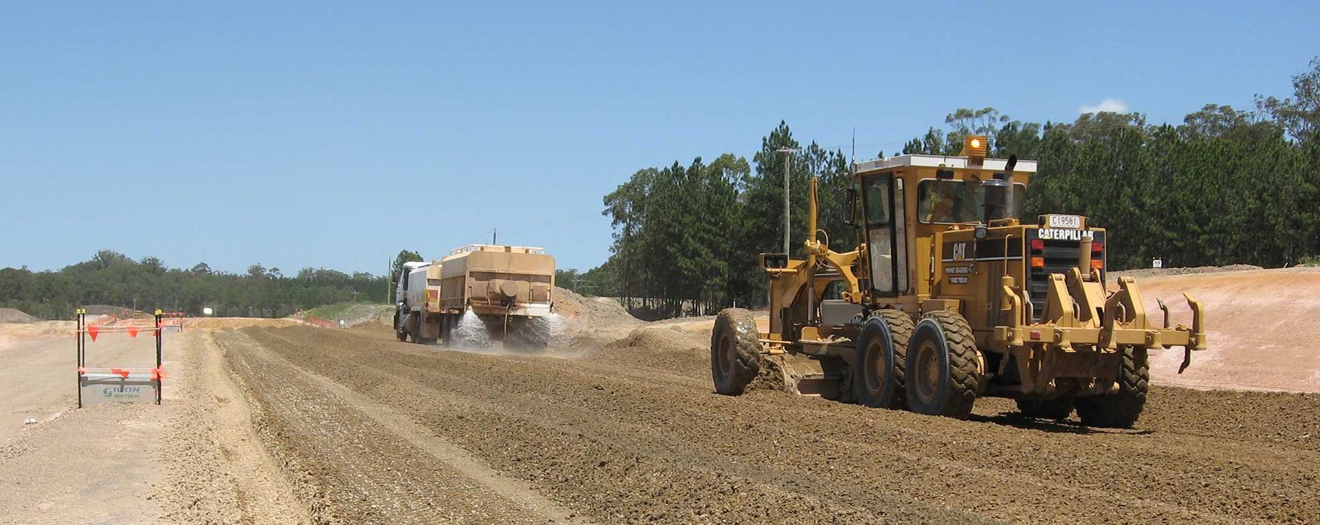 Two bulldozers are working on a dirt road