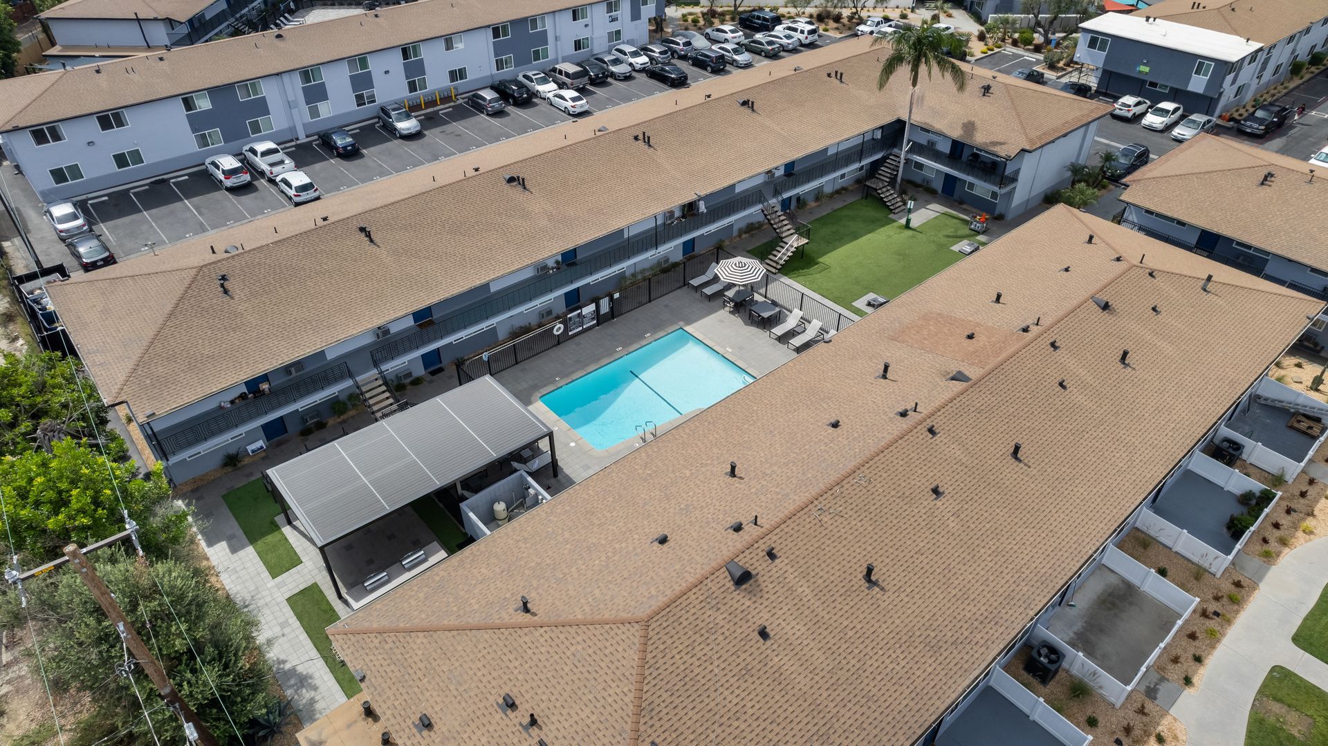An aerial view of a large apartment complex with a swimming pool in the middle.