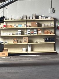 A warehouse floor featuring blue conveyor belt systems above and cardboard boxes stacked on wooden pallets below.