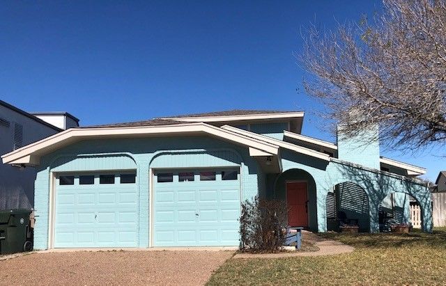 a blue house with two garage doors and a tree in front of it . | Corpus Christi, TX | GT Roofing