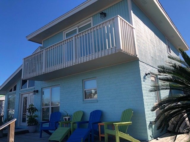 a blue house with a balcony and chairs in front of it | Corpus Christi, TX | GT Roofing