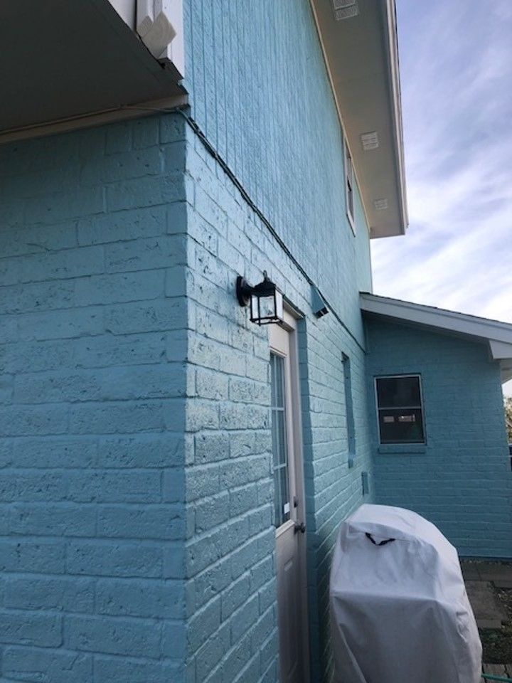 a blue brick house with a grill on the side of it . | Corpus Christi, TX | GT Roofing