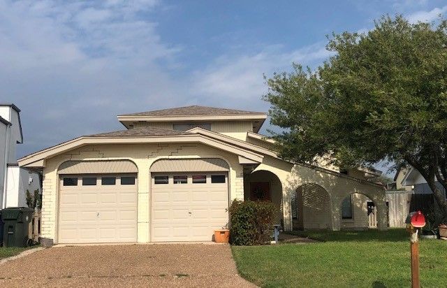 a house with two garage doors and a driveway in front of it . | Corpus Christi, TX | GT Roofing