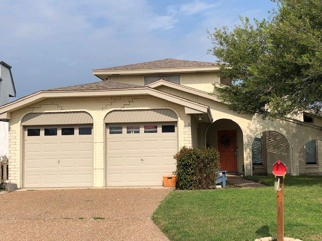 a house with two garage doors and a mailbox in front of it .  | Corpus Christi, TX | GT Roofing
