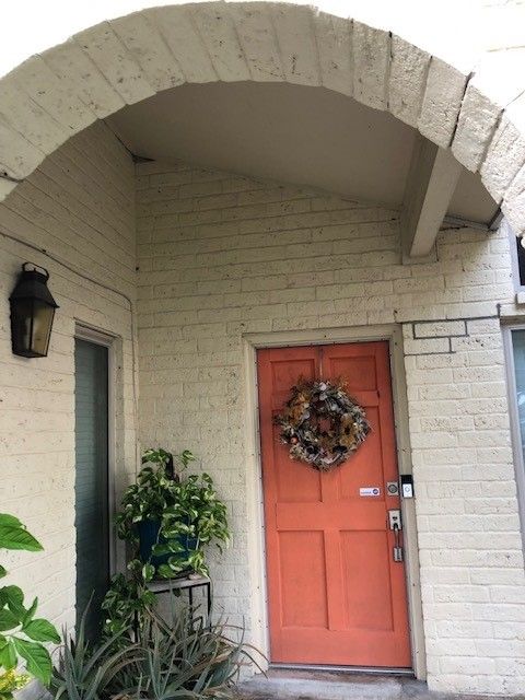 a white brick house with an orange door and a wreath on it | Corpus Christi, TX | GT Roofing