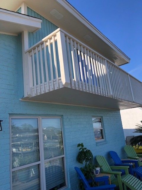 a blue house with a balcony and blue chairs  | Corpus Christi, TX | GT Roofing