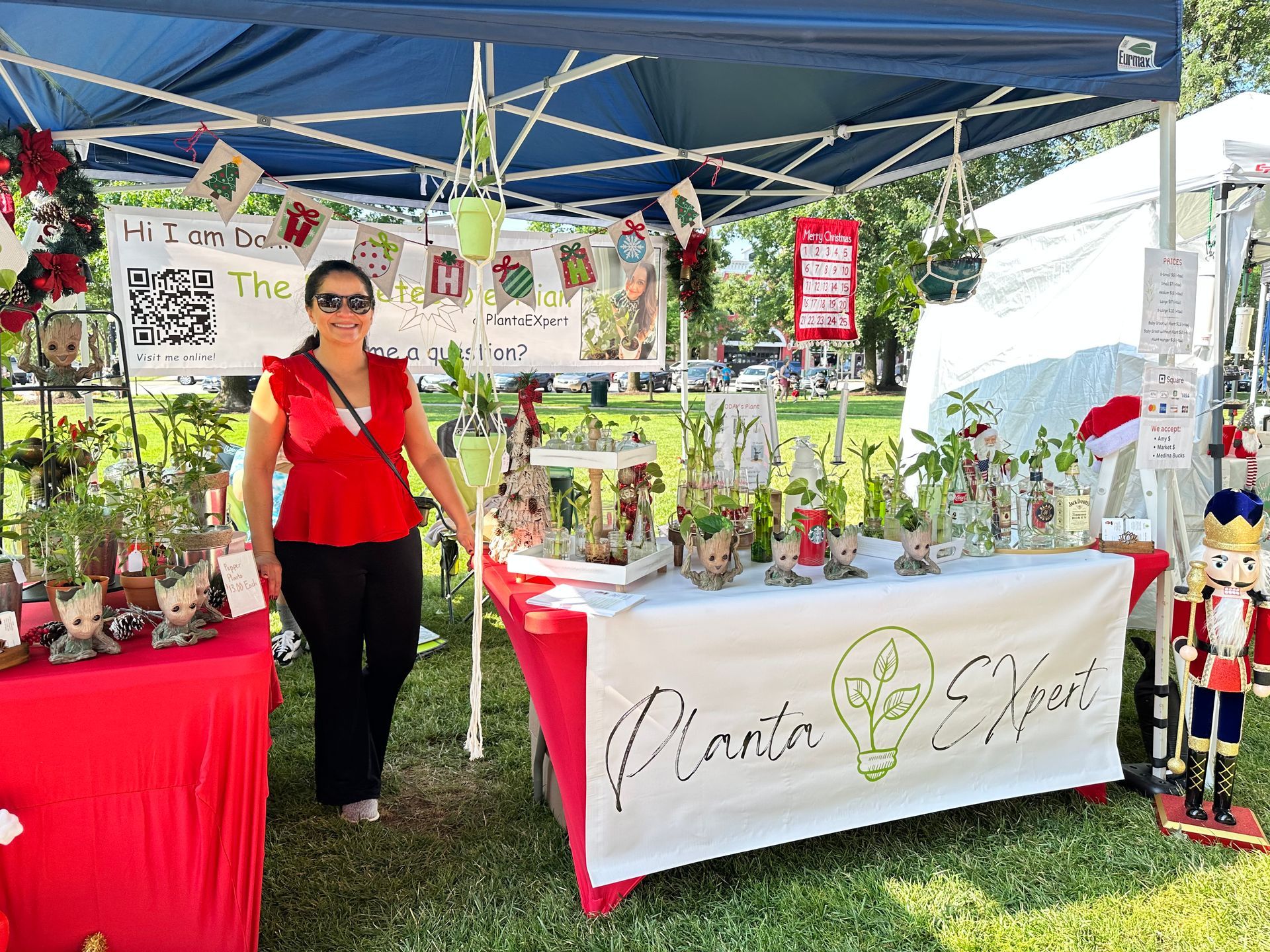 Dani is standing in front of a table at a farmers market.