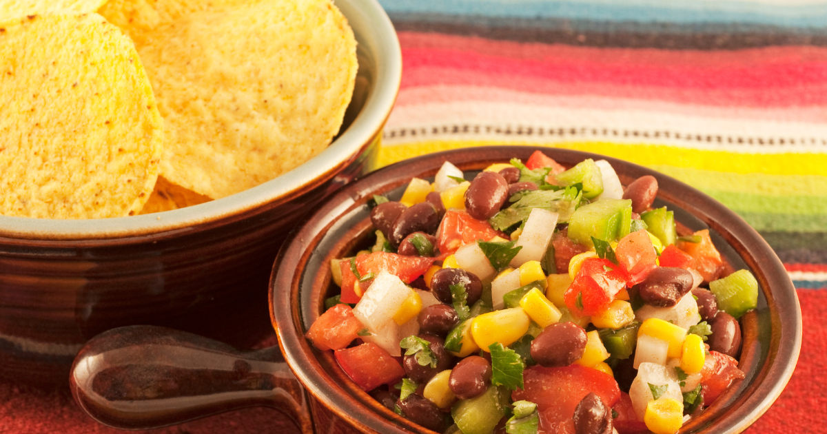 A bowl of salsa next to a bowl of tortilla chips.