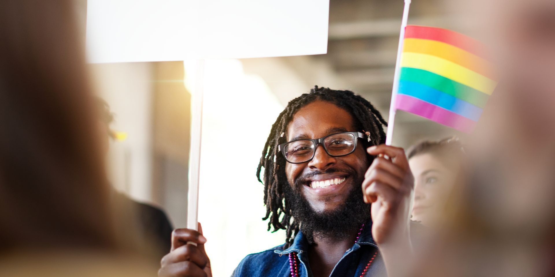 Scales of justice on a desk with a law book and two people blurred in the background.