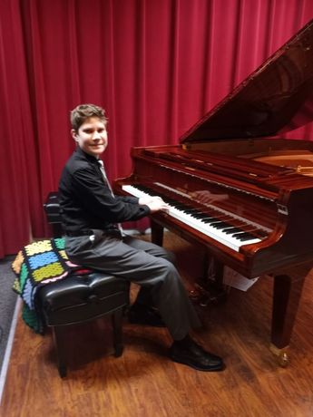 A young man is sitting in a chair playing a piano.