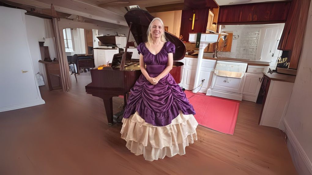 A woman in a purple dress is standing in front of a piano.