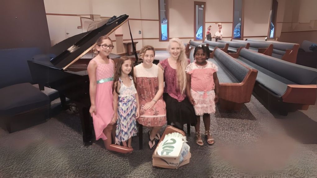 A group of young girls are posing for a picture in front of a piano in a church.