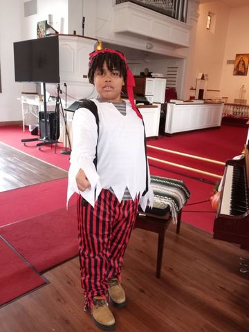 A young boy in a pirate costume is standing in a church