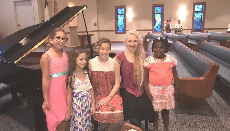 A group of young girls are standing in front of a piano in a church.