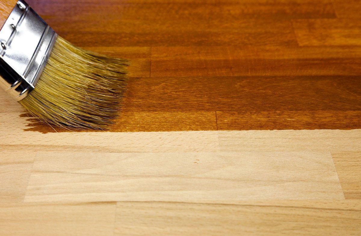 A person is painting a wooden surface with a brush.