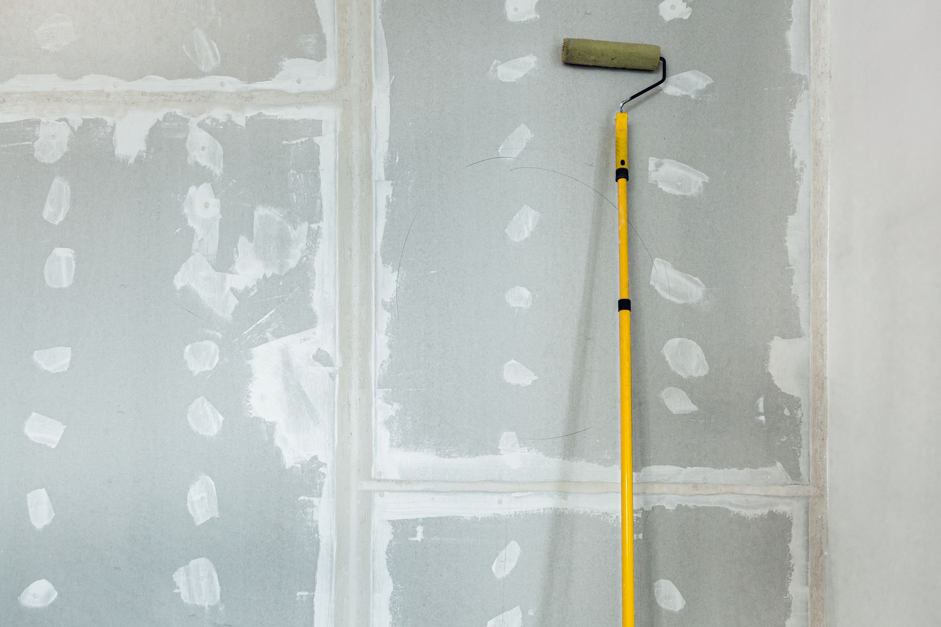 A paint roller is being used to paint a wall.