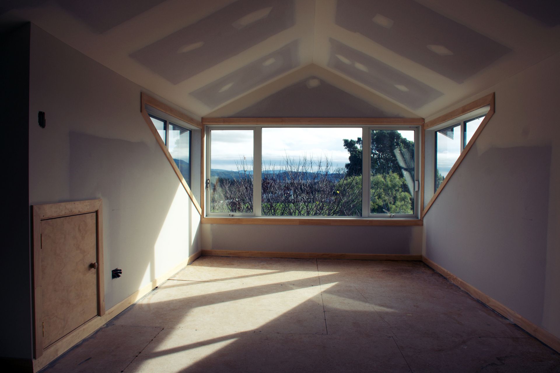 An empty room with a large window and a view of a forest.