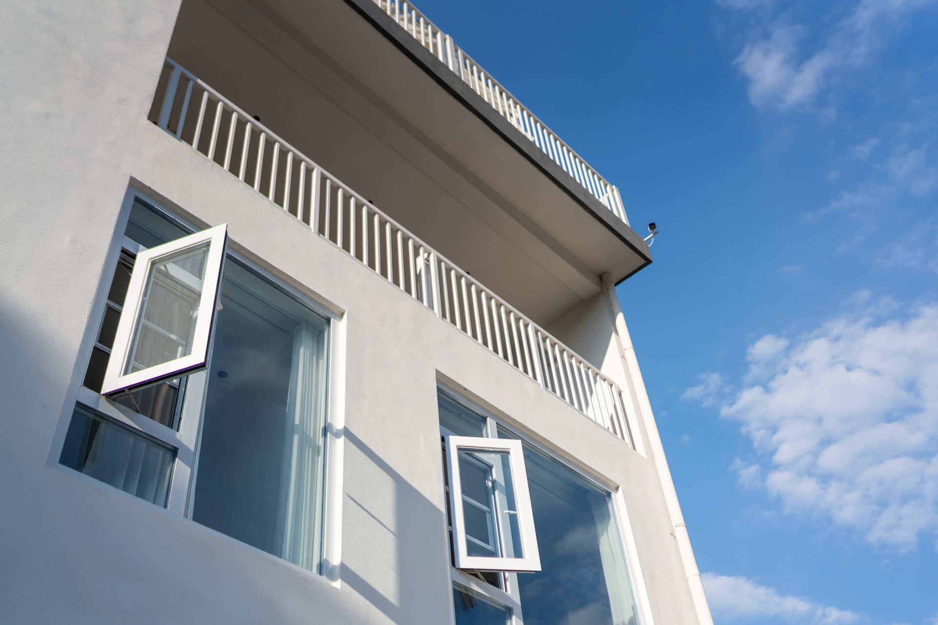 A white building with a balcony and two windows open
