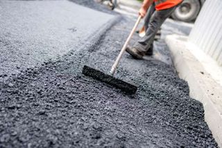 Worker levelling fresh asphalt -Crack filling in Glenwood, IA