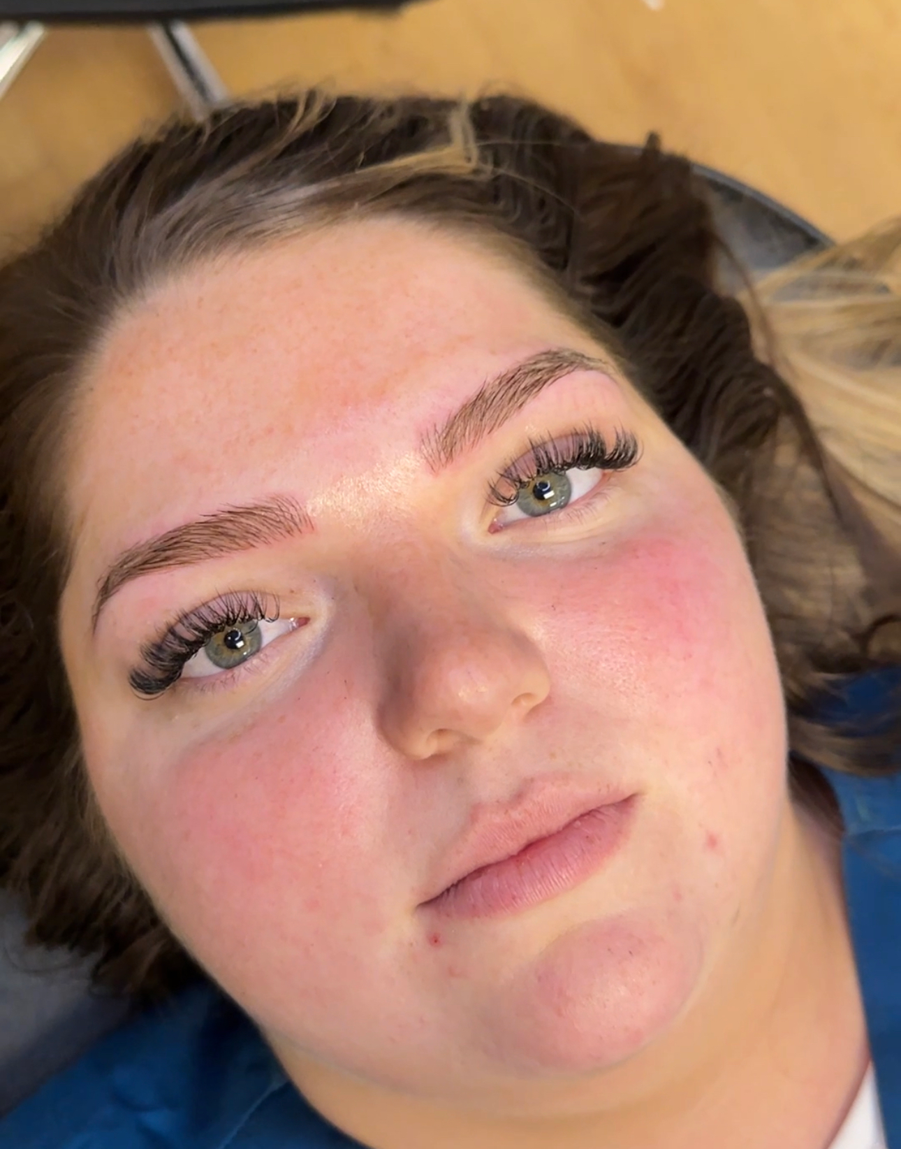 A close up of a woman 's face with green eyes and red cheeks.