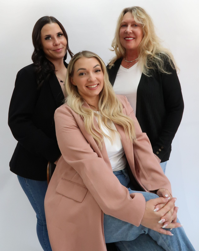 Woman applying mascara, smiling, against a white background.