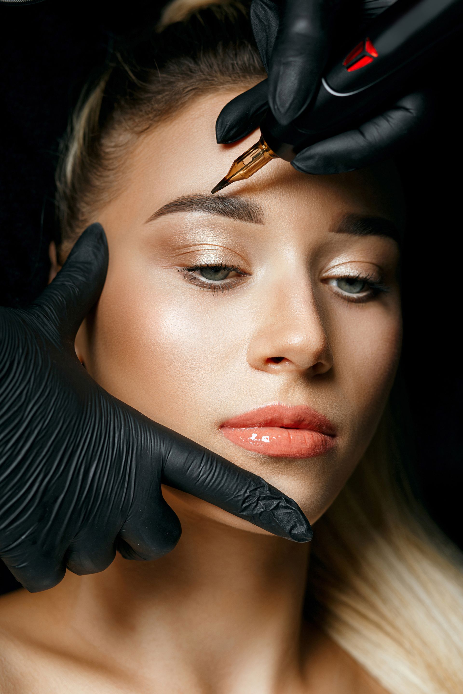 a woman is getting her eyebrows tattooed by a person wearing black gloves