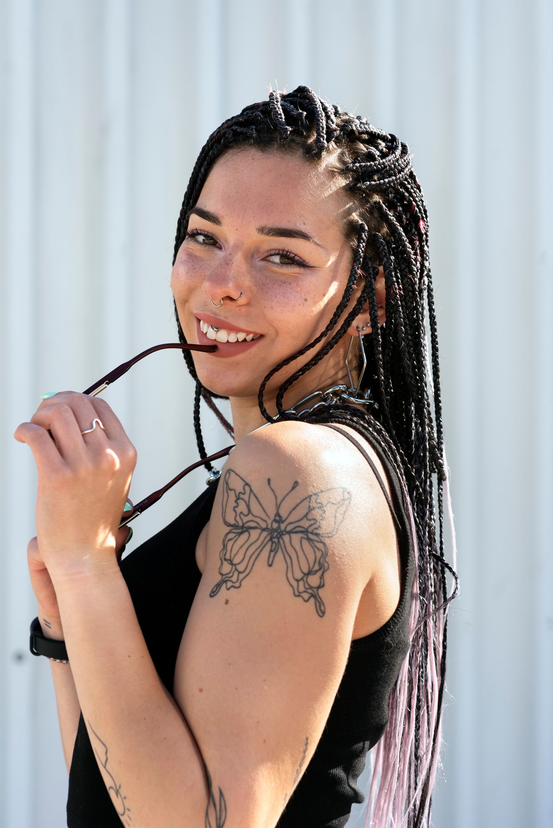 A woman with braids and a tattoo of a butterfly on her arm.