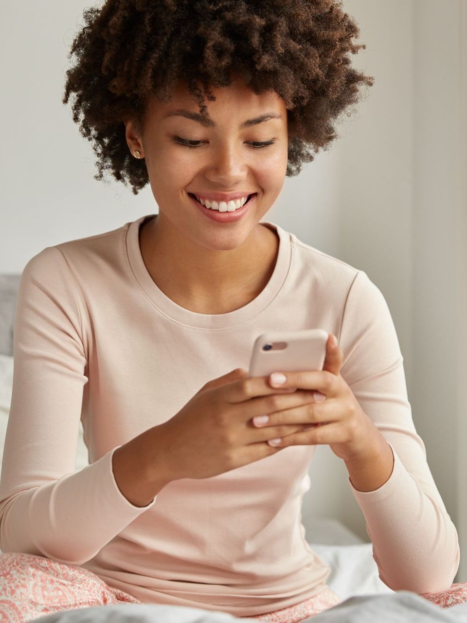 a woman is sitting on a bed looking at her phone