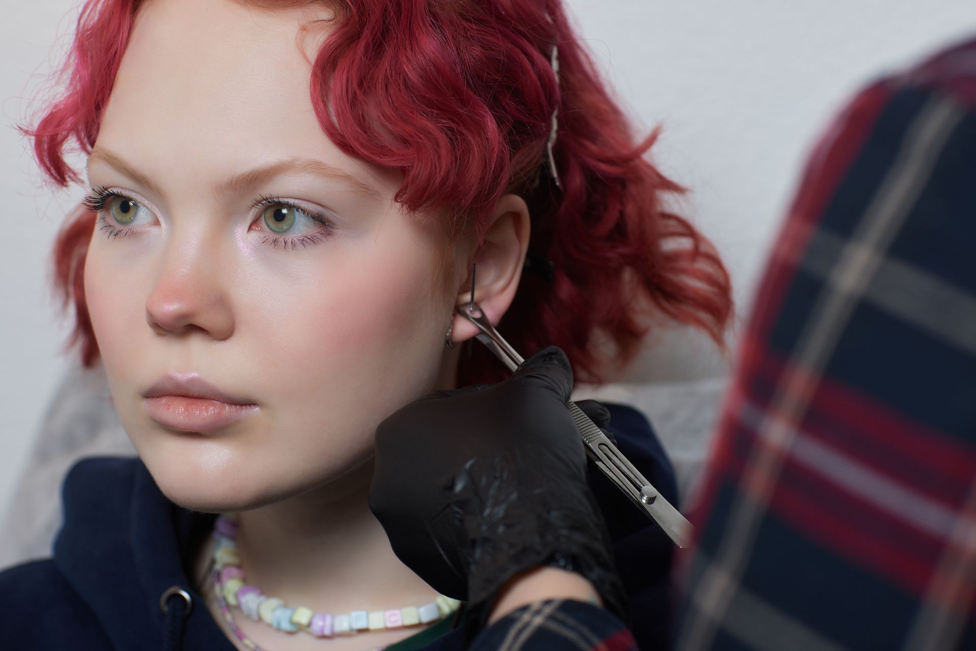 a woman with red hair is getting her ear pierced