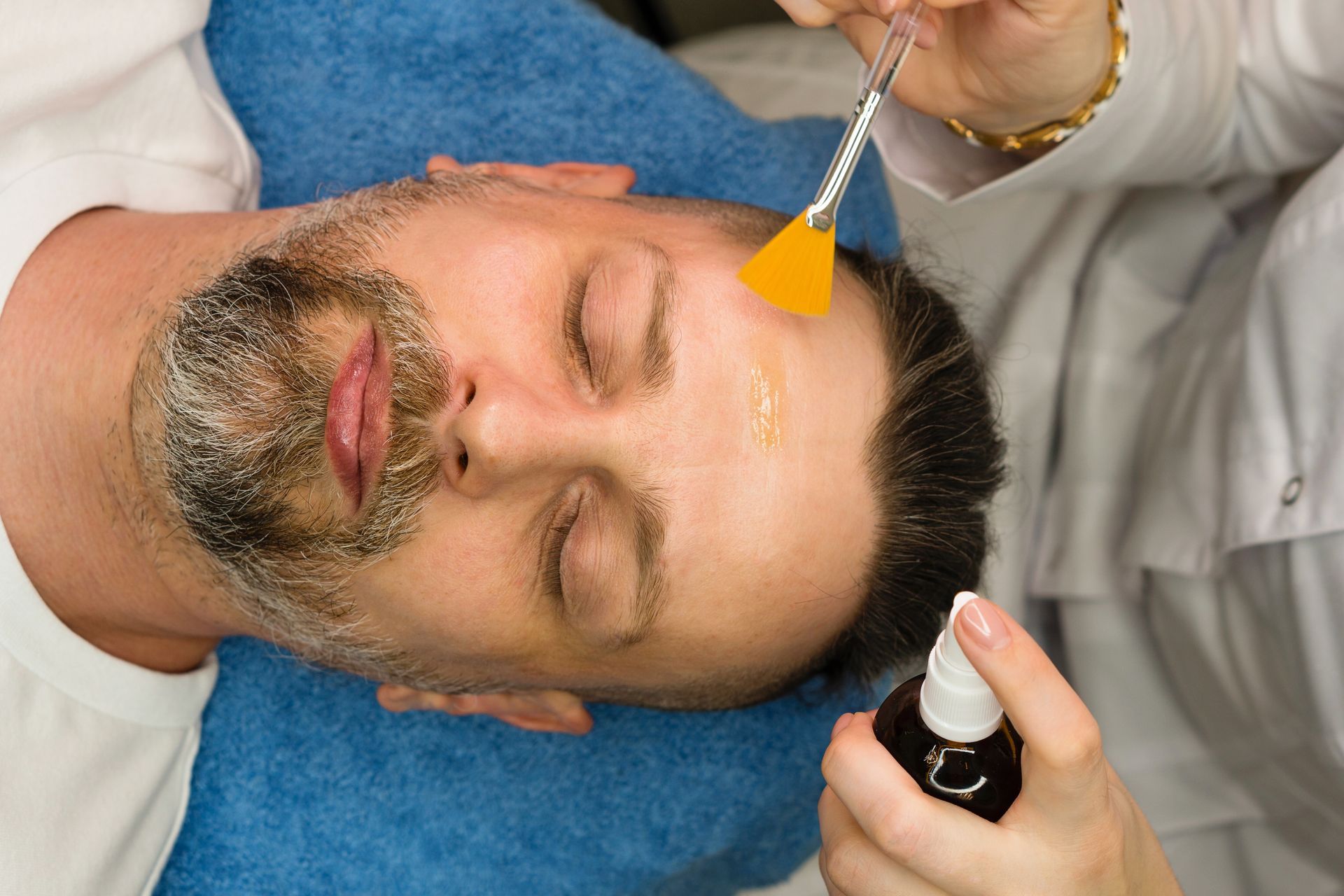 A man with a beard is getting a facial treatment.