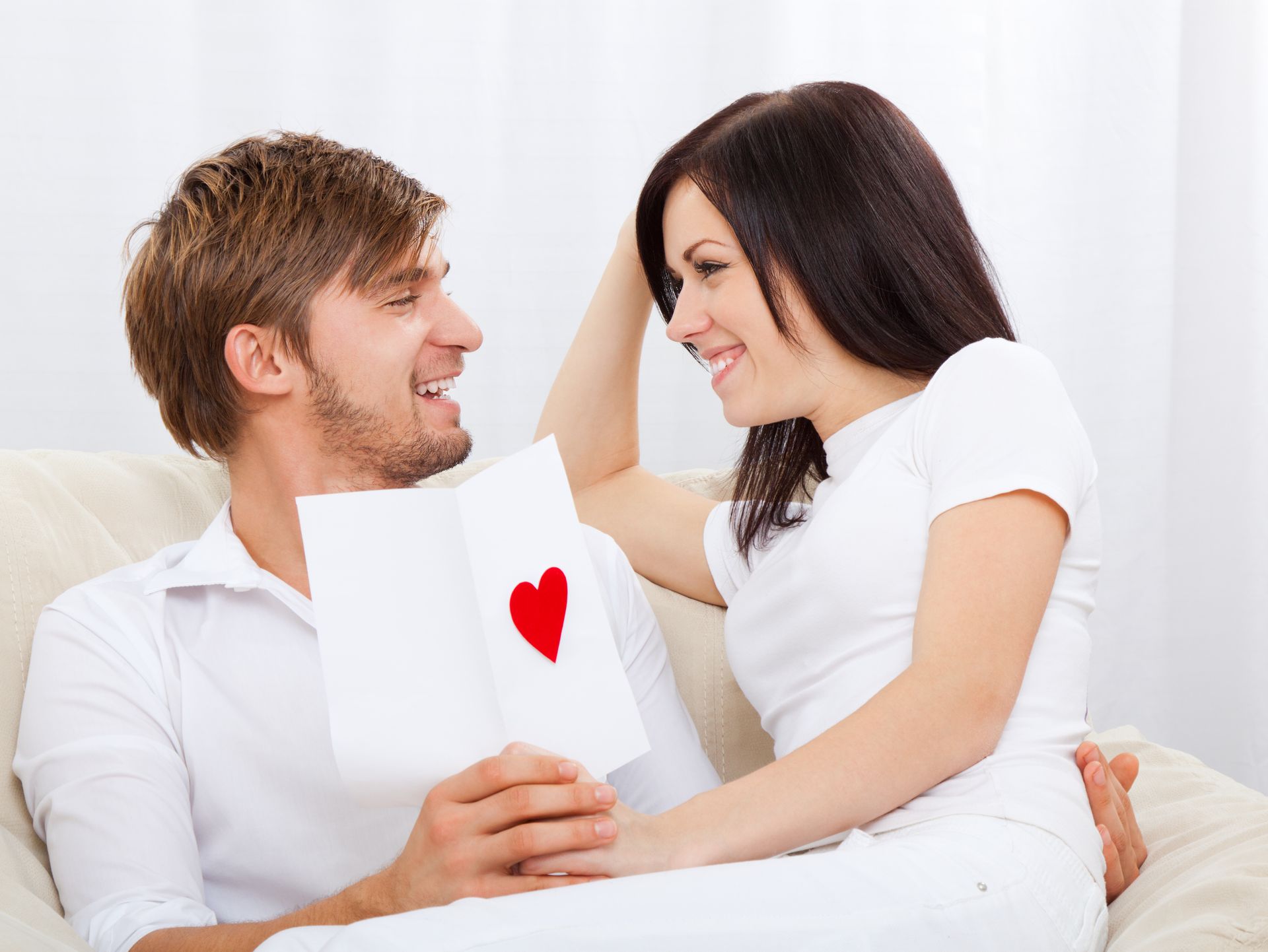 A man is holding a card with a red heart on it