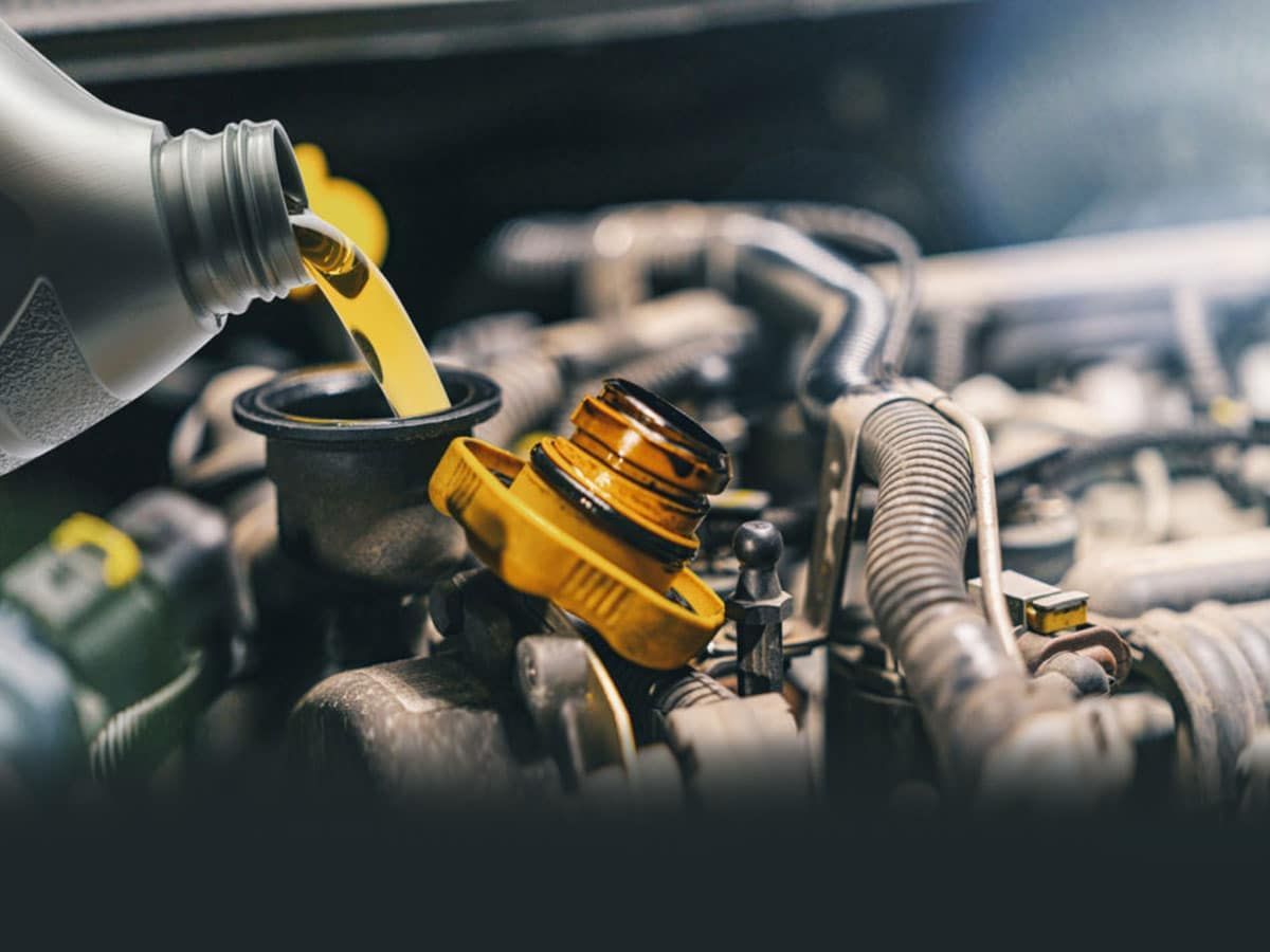 A person is pouring oil into a car engine. Marquette, MI | Barron’s Auto Repair