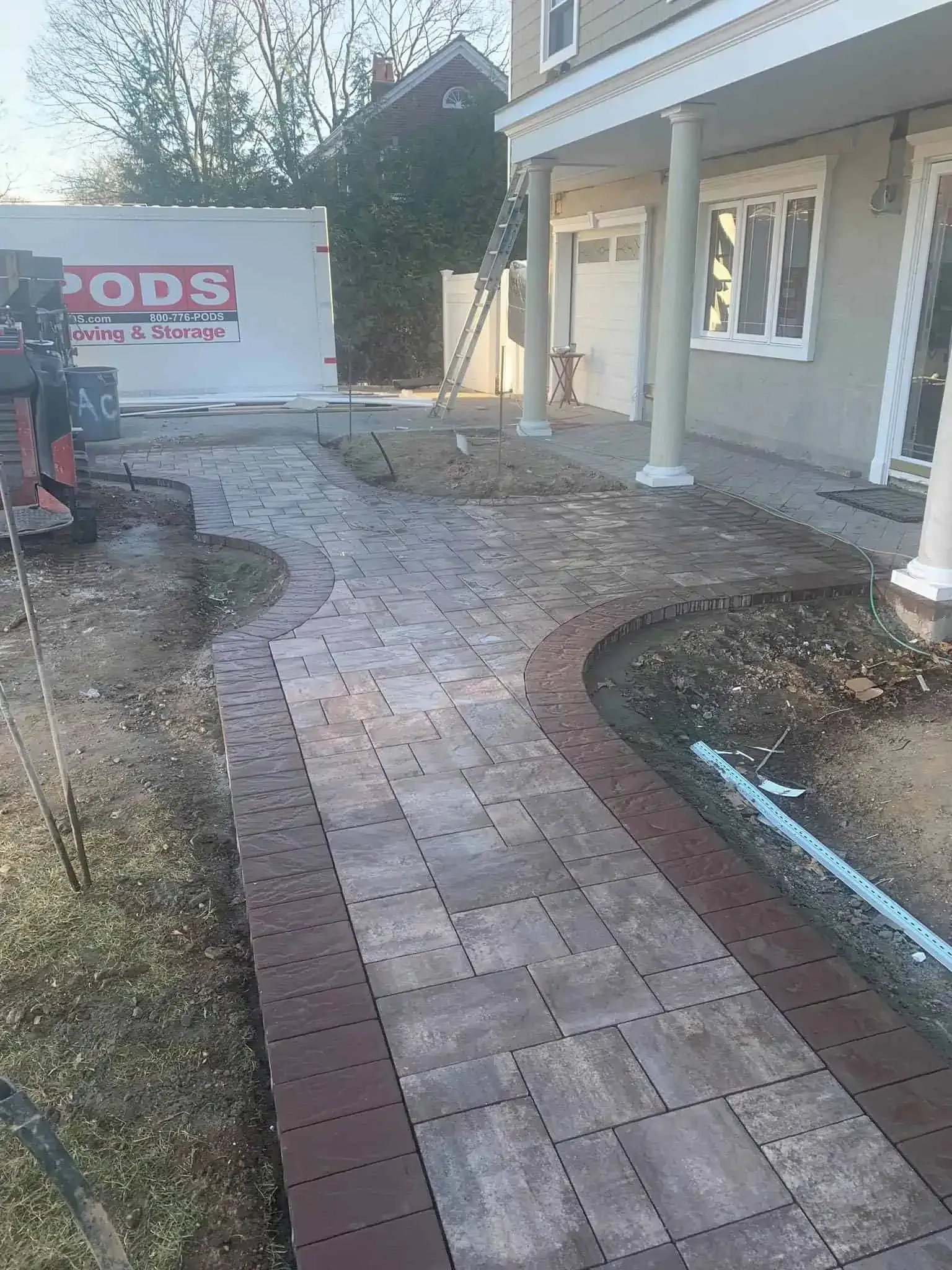 A brick walkway is being built in front of a house.