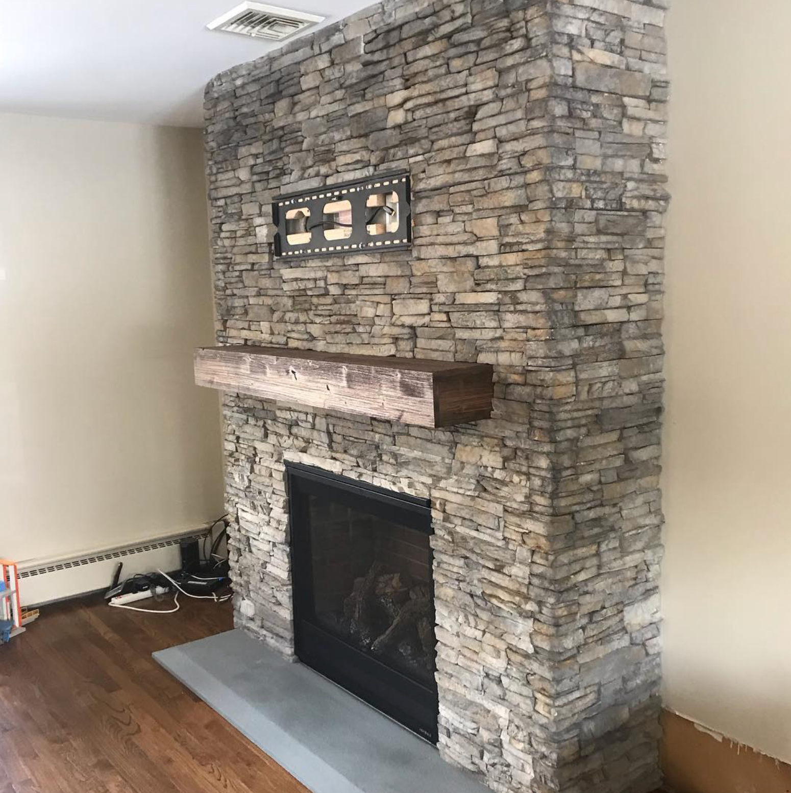 A stone fireplace with a wooden mantle in a living room