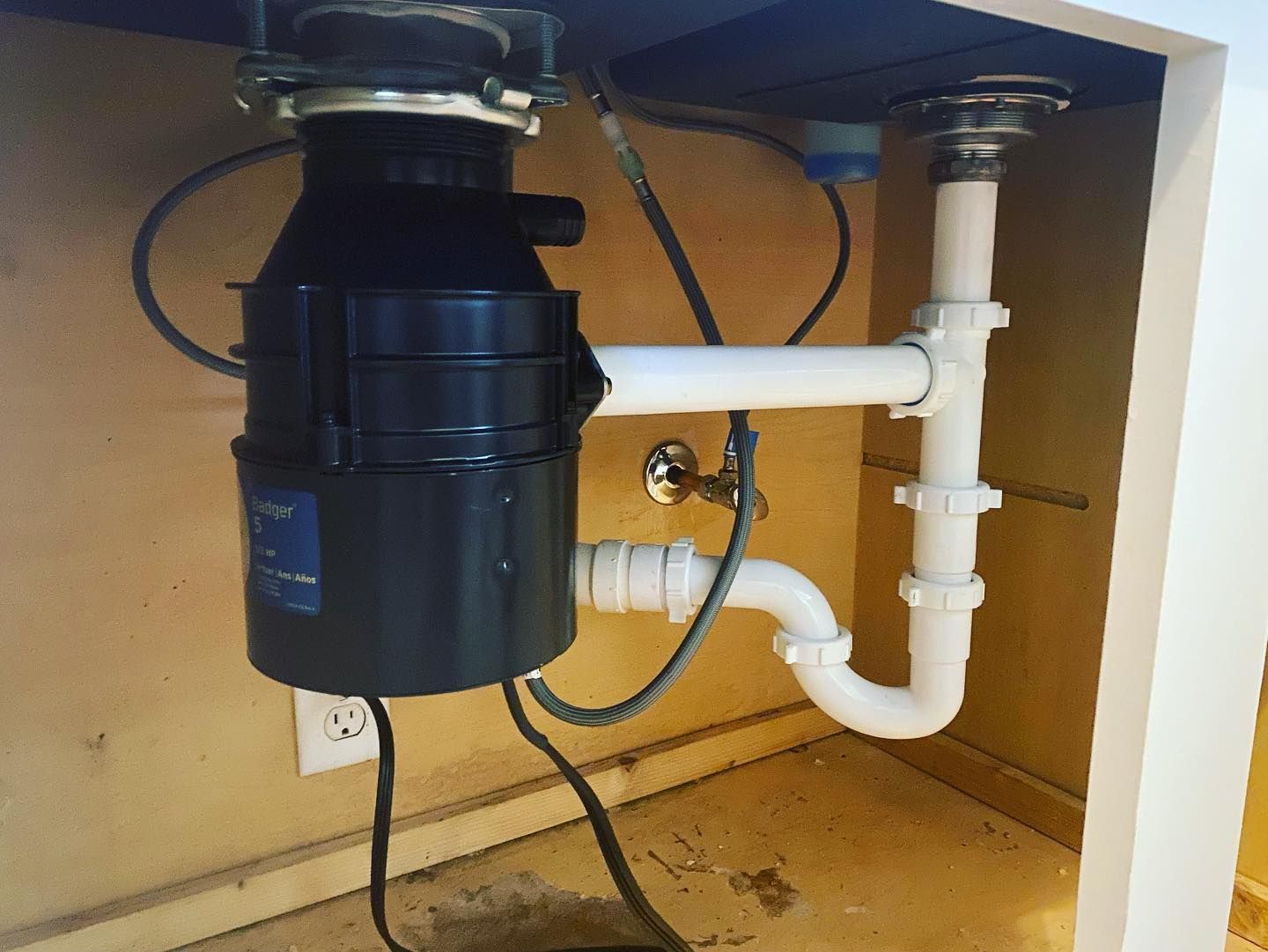 Under-sink plumbing setup with a garbage disposal and white pipes connected to a sink drain.
