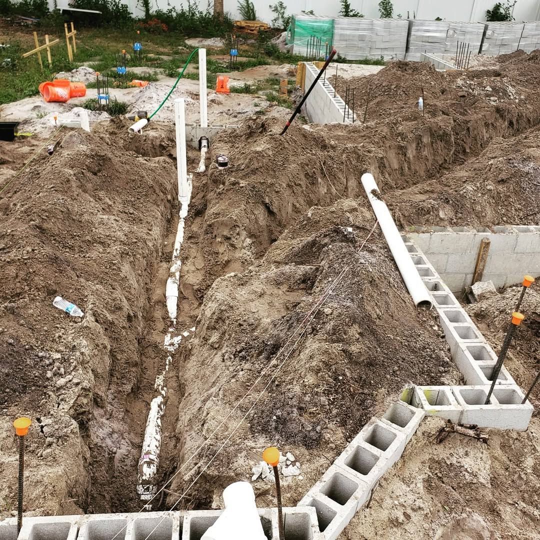 Construction site with trenches, plumbing, and cinder block foundation.