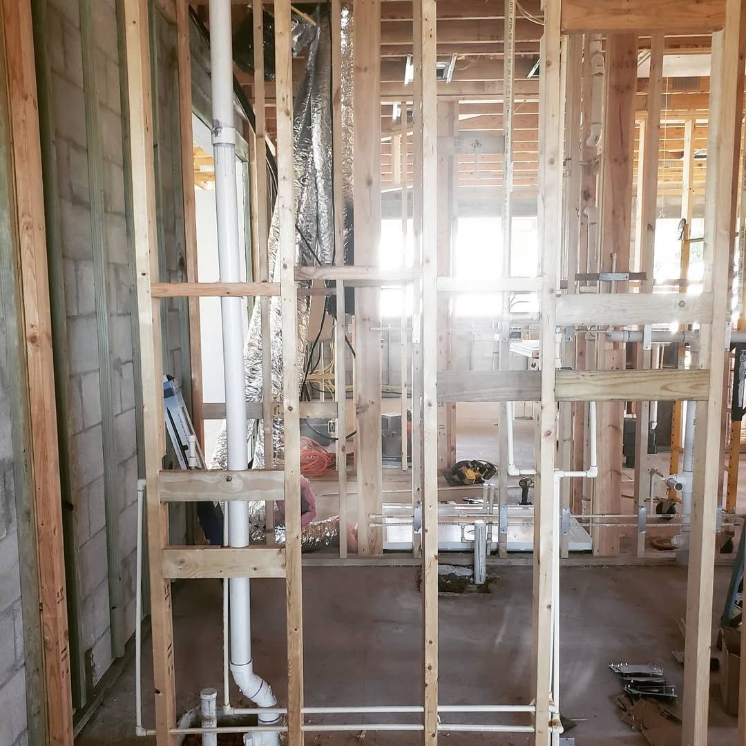 Interior view of a building under construction, showing wooden framing and plumbing fixtures in place.
