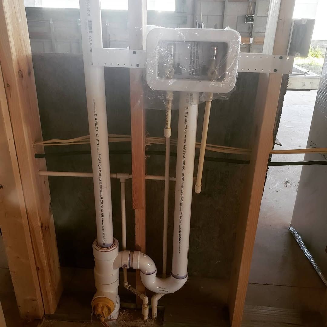 Plumbing installation in a framed wall: white PVC pipes, copper tubing, and electrical box.