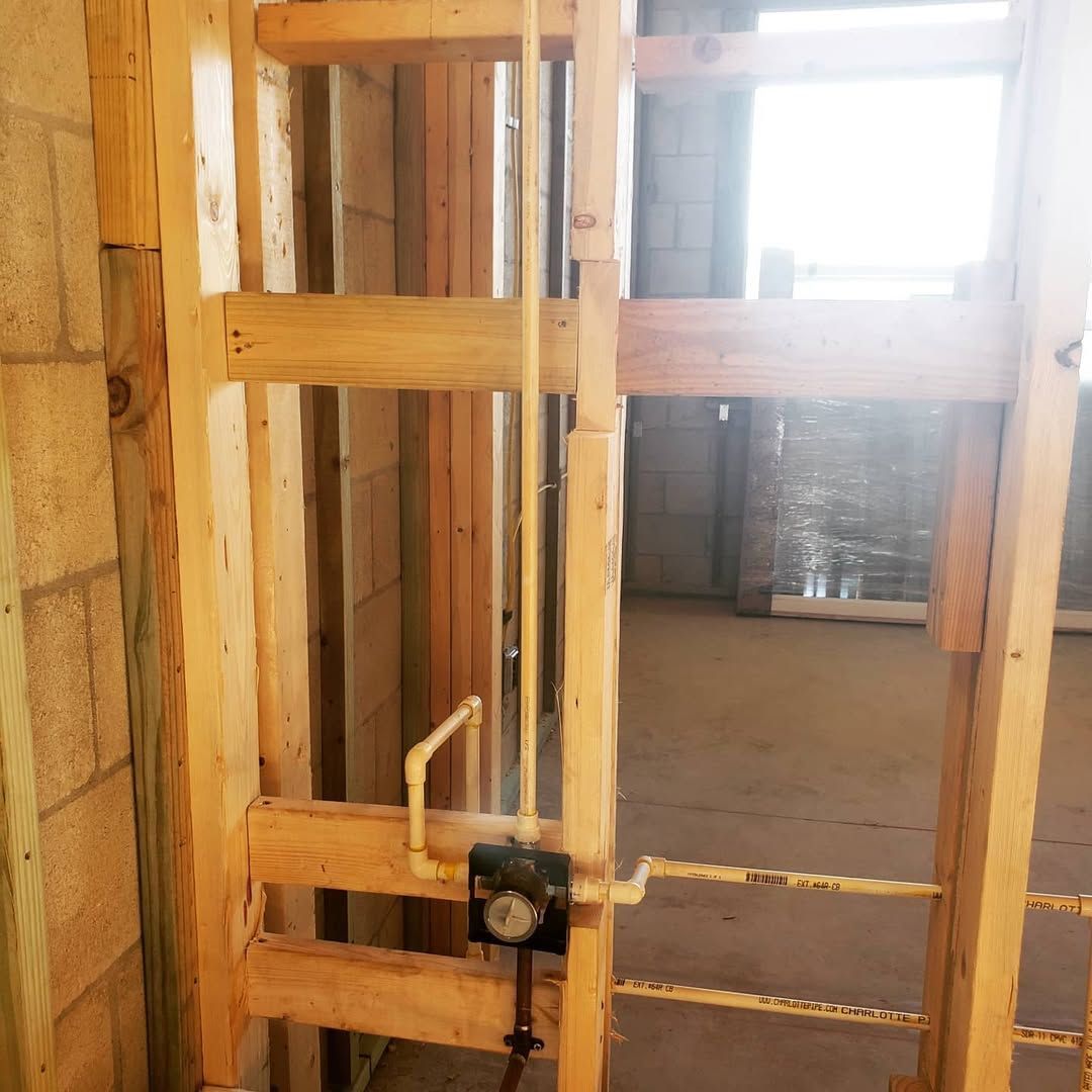 Wooden framing with installed plumbing fixtures in a construction setting.