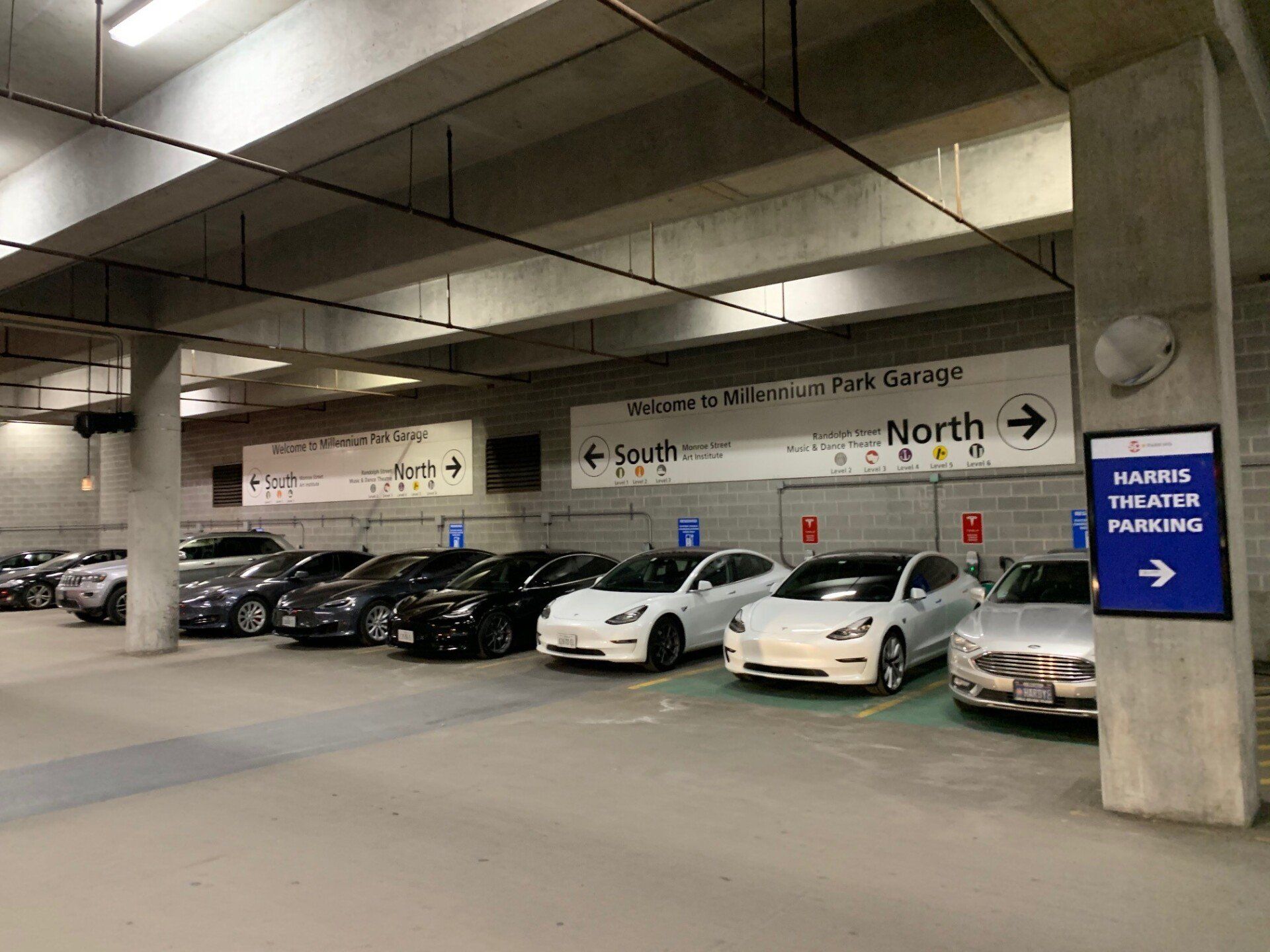 Cars parked in an indoor parking garage with directional signs.