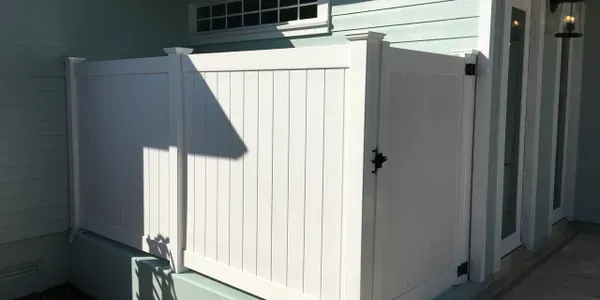 A white fence is sitting on the side of a house.