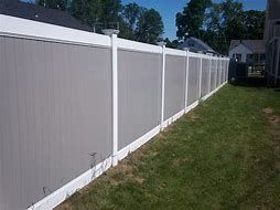 A gray and white vinyl fence surrounds a lush green yard.