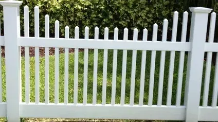 A white picket fence is surrounded by green grass