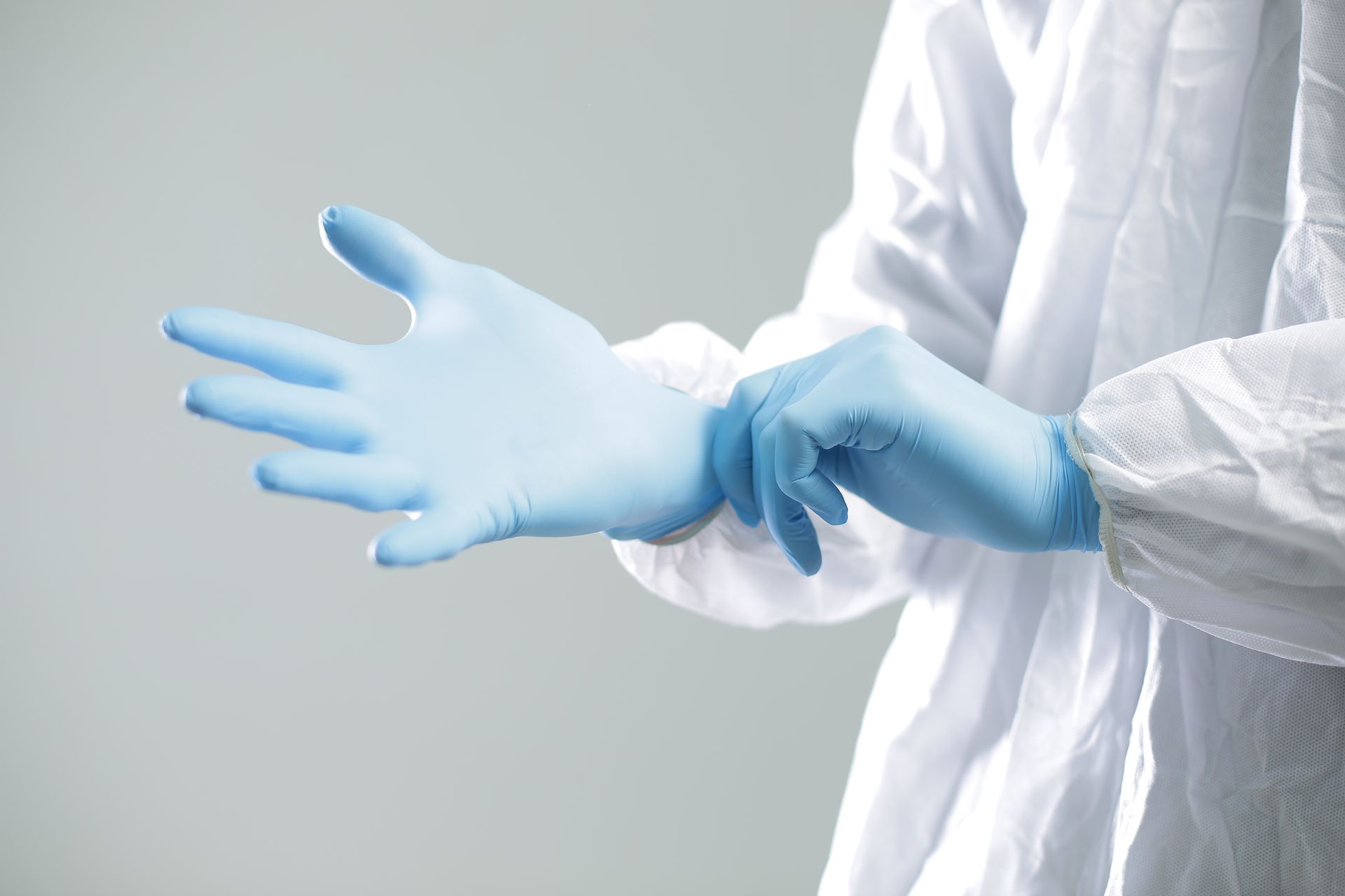 A person is putting on a pair of blue gloves.