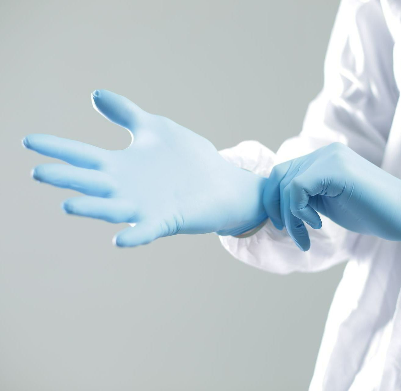 A person is putting on a pair of blue gloves