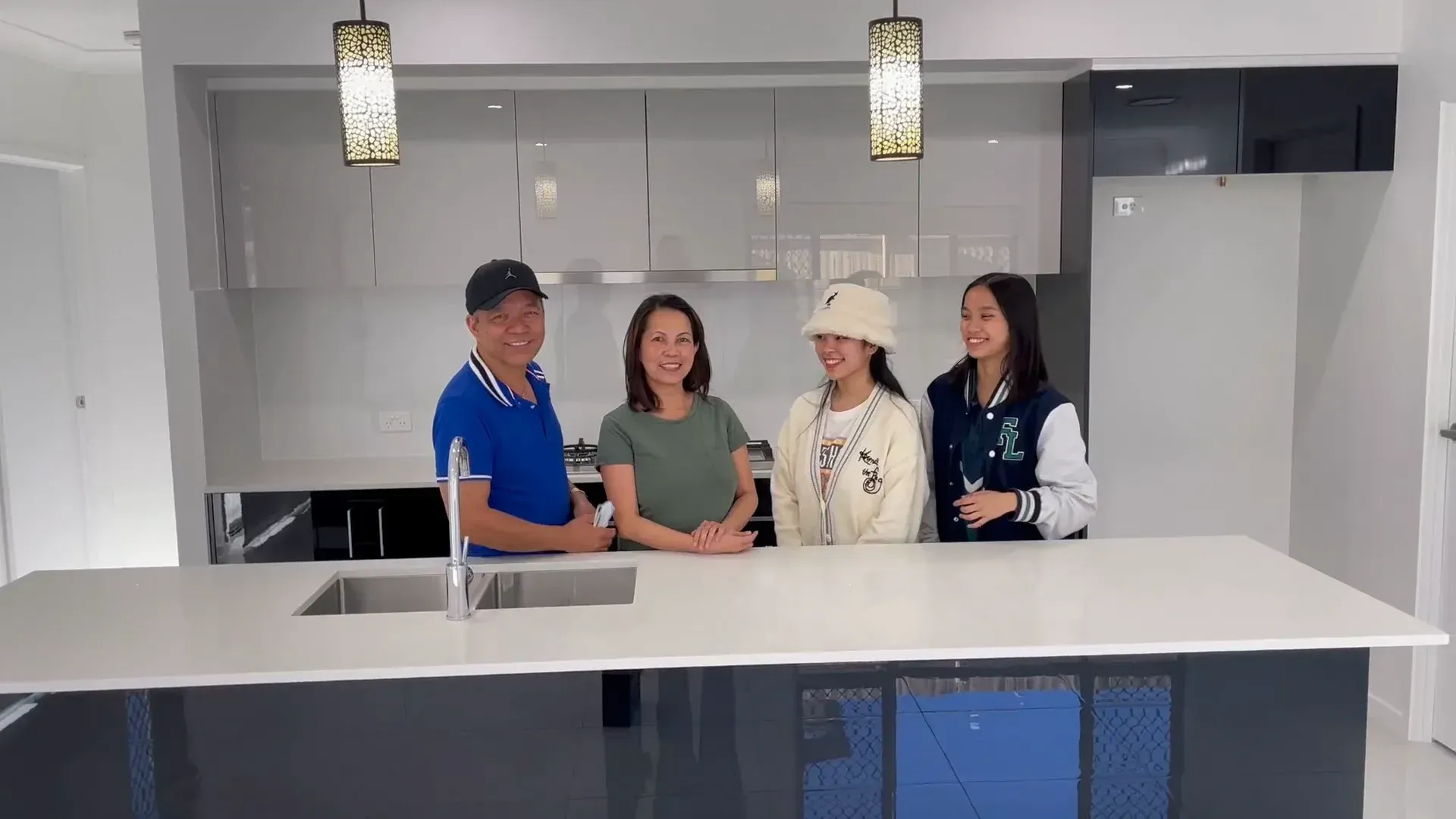 Family poses in a modern kitchen with gray cabinets and white countertop.