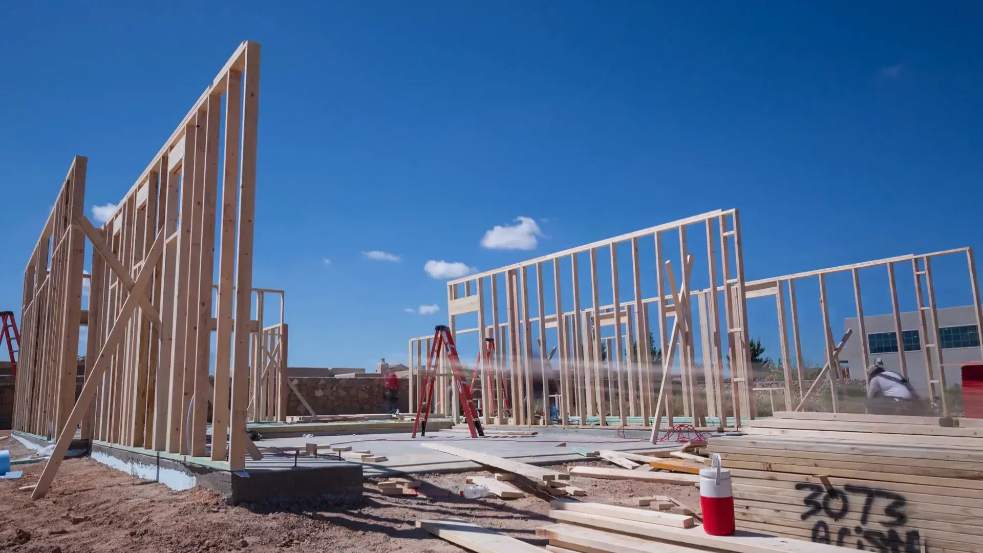 Wooden frame of a building under construction against a bright blue sky.