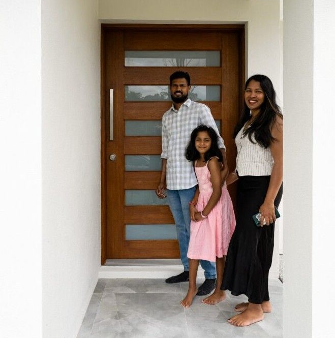 Modern beige house with a driveway, garage, and front yard landscaping.